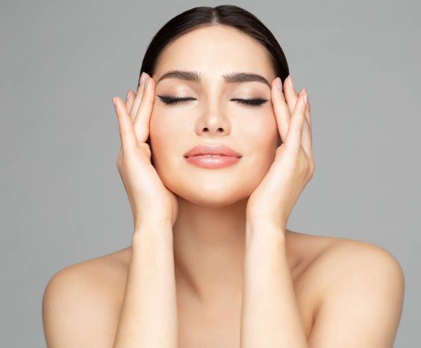 A woman is touching her face with her hands