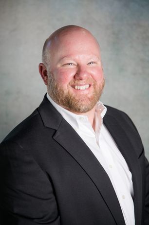 A man in a suit and white shirt is smiling for the camera.