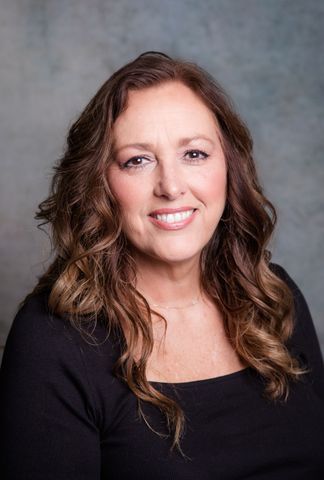 A woman in a black sweater is smiling for the camera.