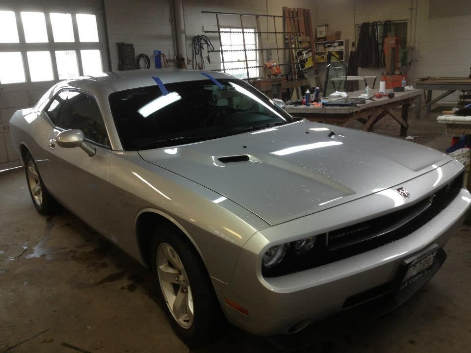 Silver sports car parked inside a cluttered garage.