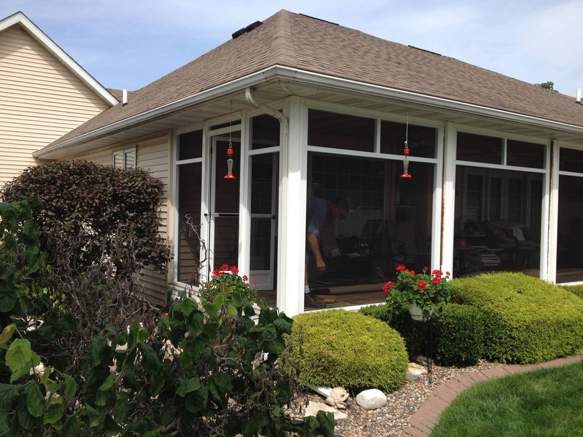 Suburban house with screened porch, white trim, and landscaped front yard