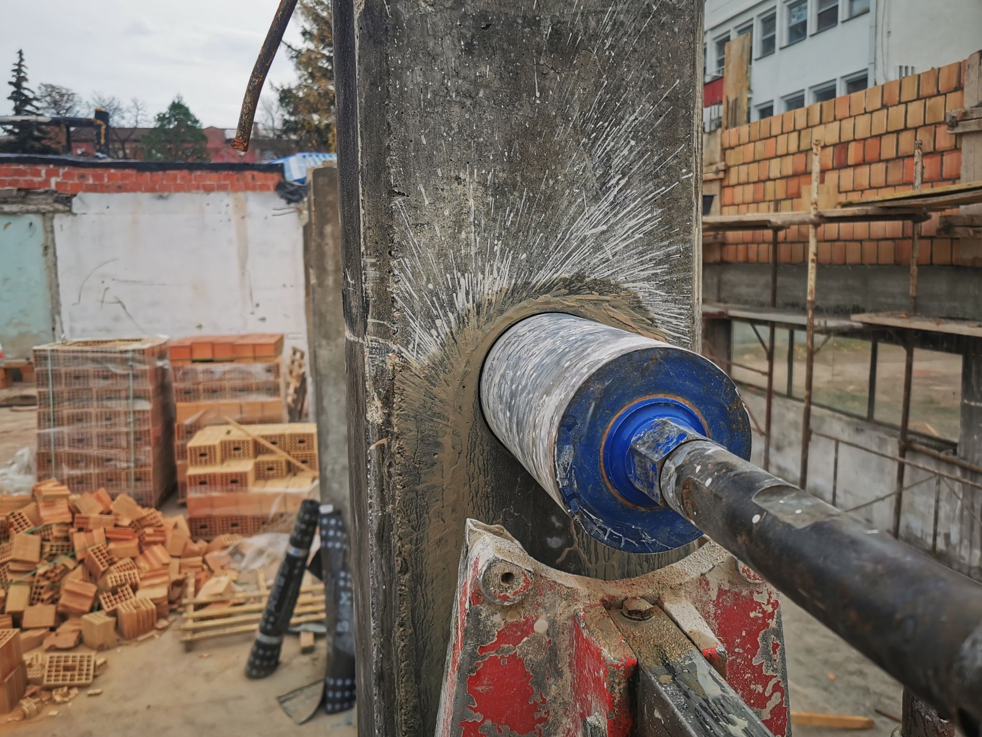 A coring machine drilling a large hole in a concrete pillar at a construction site.