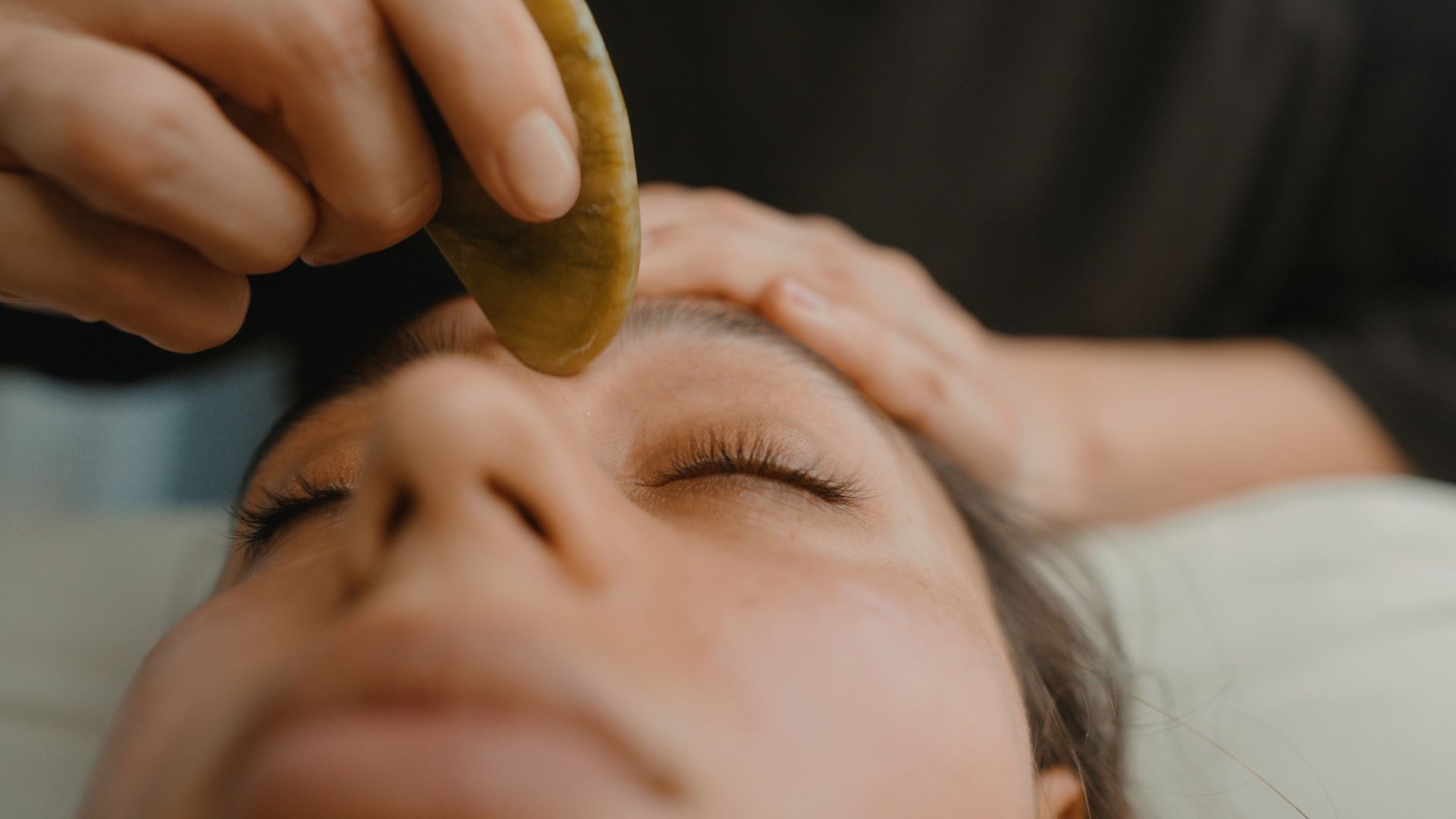Hands holding a smooth stone over a person’s closed eyes during a facial massage Hands holding a smooth stone over a person’s closed eyes during a facial massage