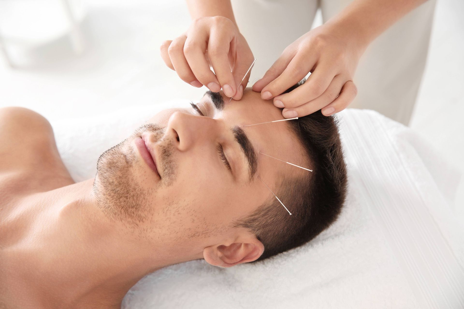 Eyebrow threading treatment on a person lying back with eyes closed, in a spa setting