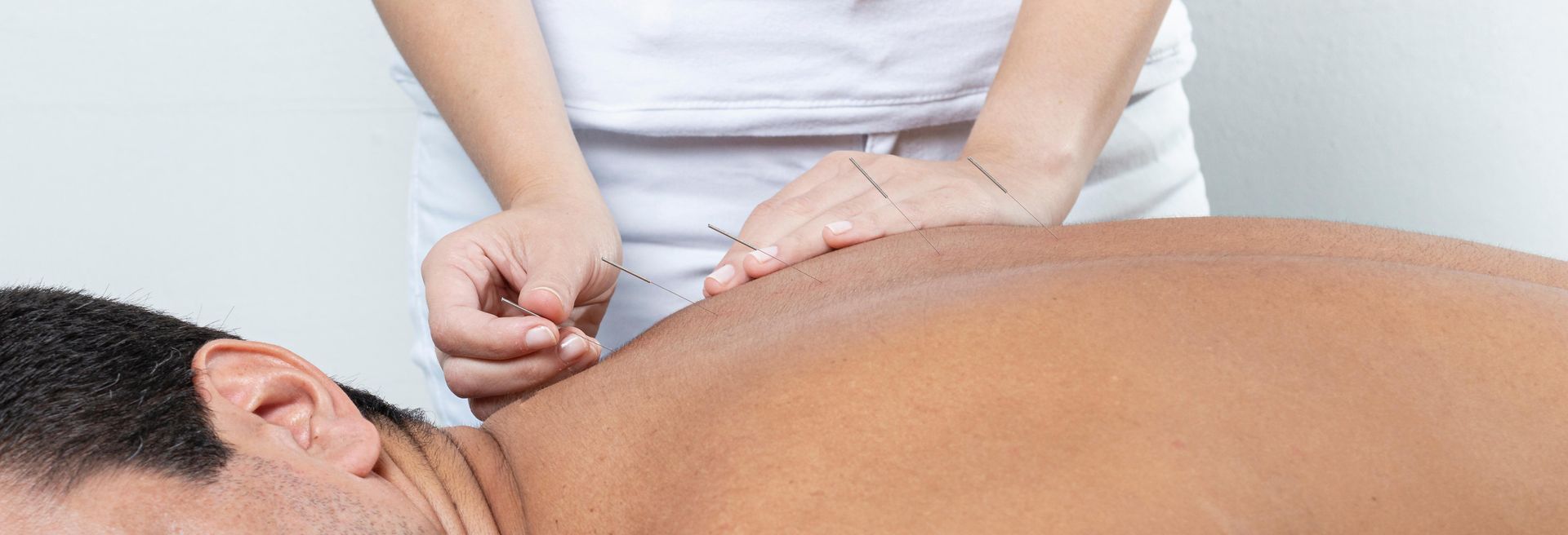 Massage therapist kneading a client’s upper back on a massage table