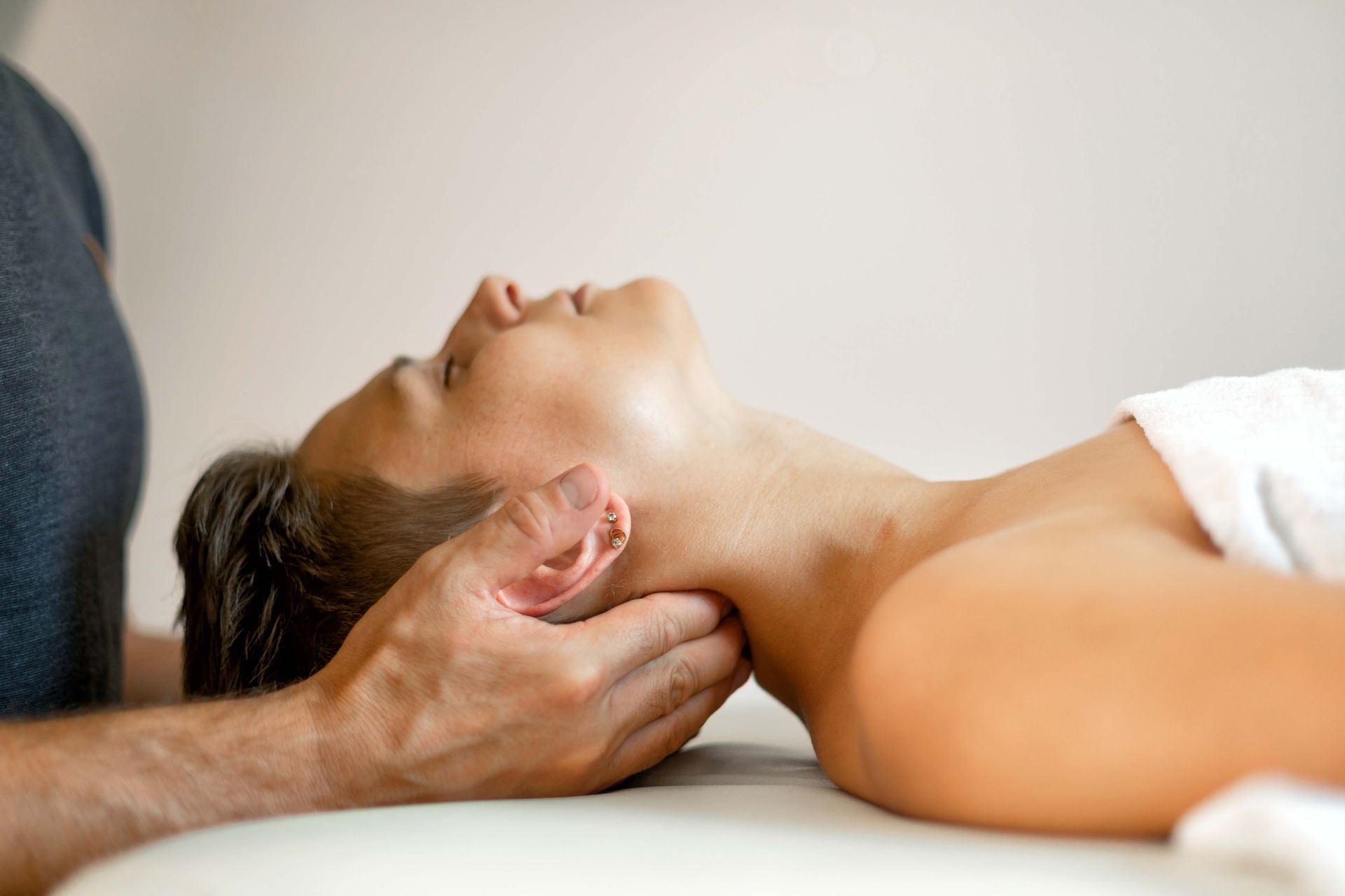 Person receiving a neck massage while lying on a table indoors