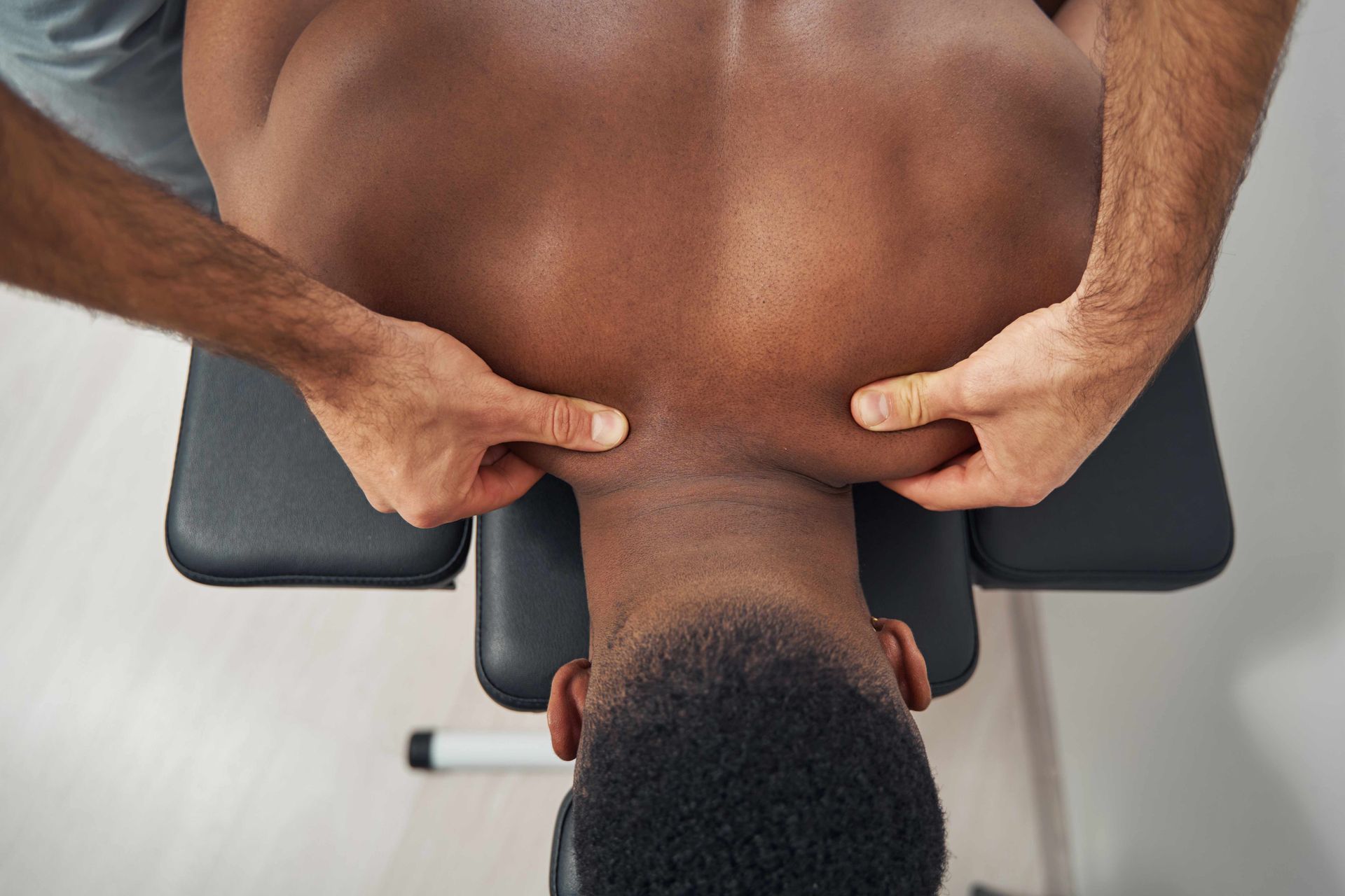 Hands pressing a person's upper back during a massage on a treatment table Hands pressing a person's upper back during a massage on a treatment table