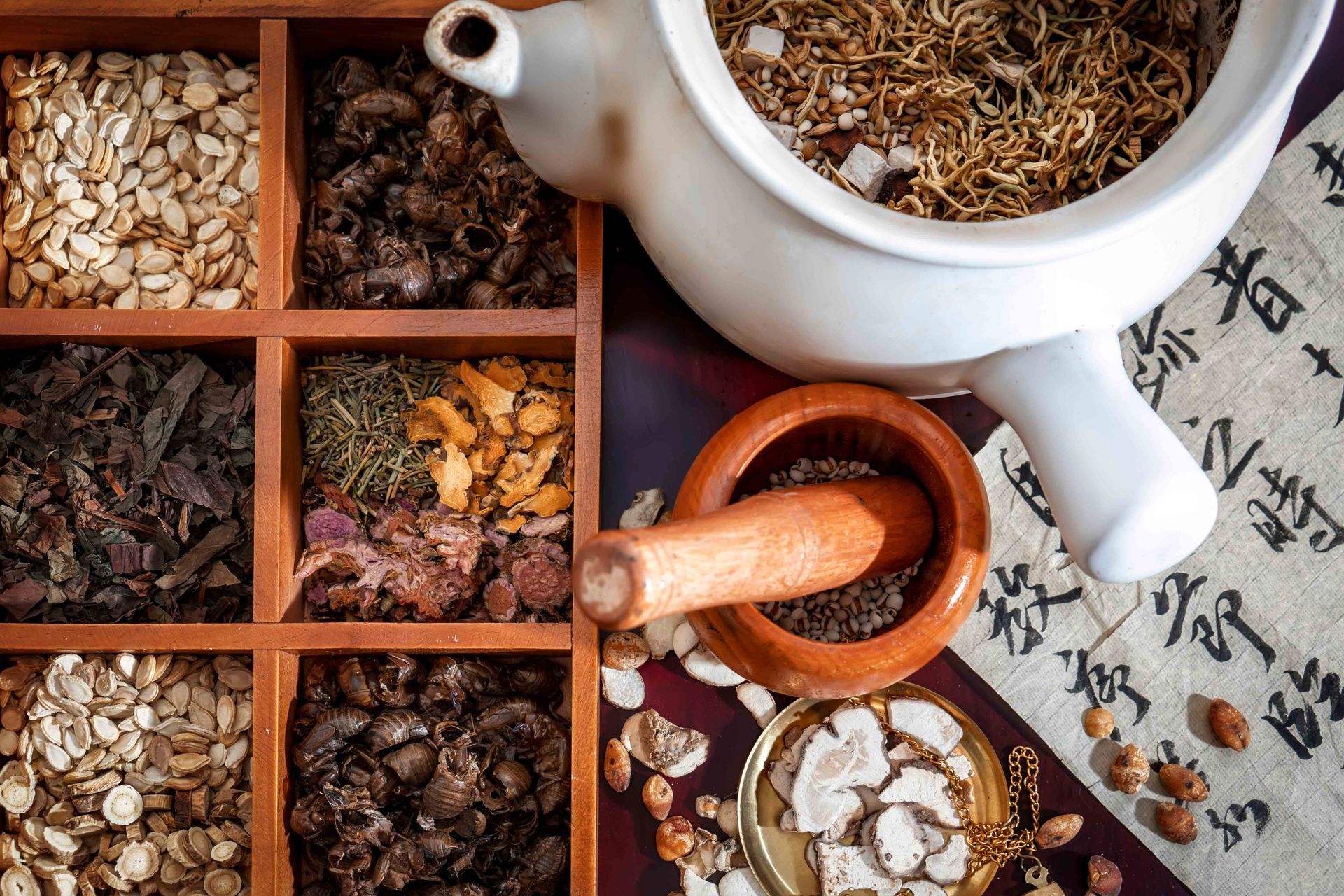 Assorted dried herbs and spices in a divided tray with ceramic bowls and a wooden spoon Assorted dried herbs and spices in a divided tray with ceramic bowls and a wooden spoon