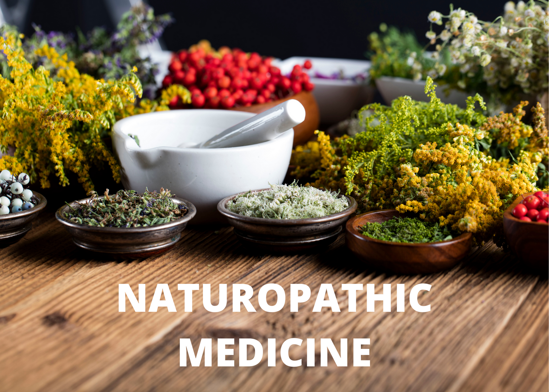 Naturopathic medicine display with herbs, flowers, bowls, and a mortar on a wooden table
