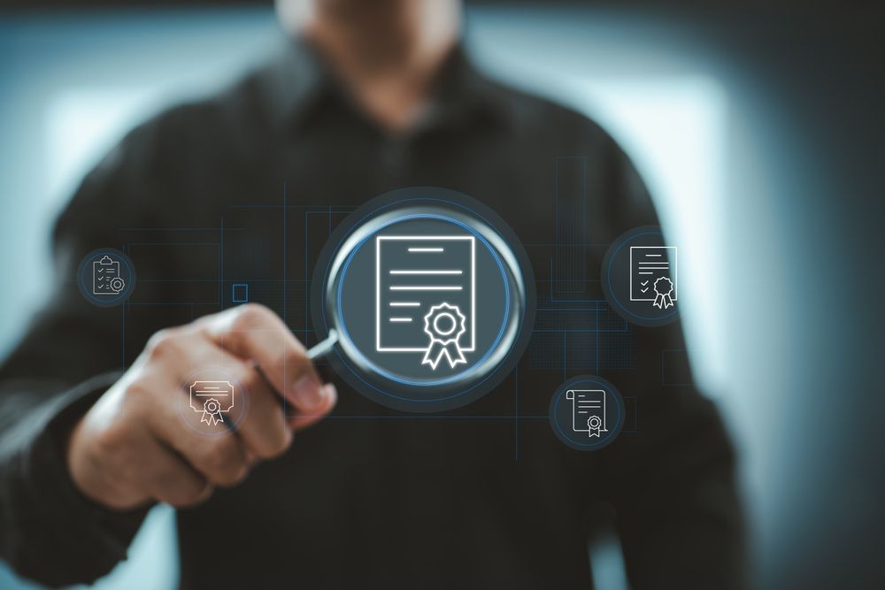 Hand reaching toward a glowing digital certificate icon with document symbols in a dark office setting