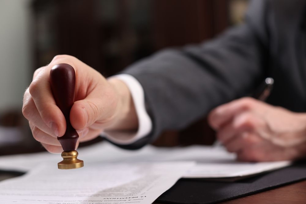 Hand stamping a document with a rubber seal at a desk
