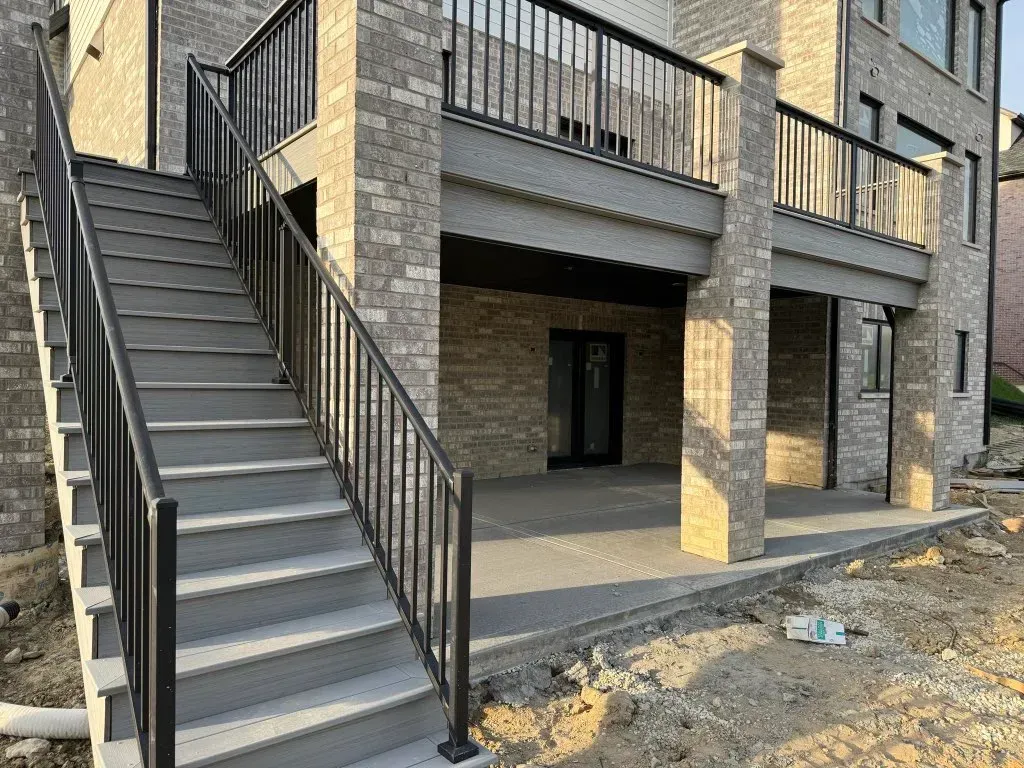Exterior of a brick apartment building with a metal staircase and balconies above a dirt lot