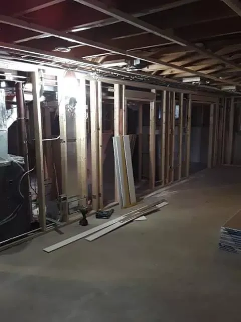 Partially finished basement with exposed studs, drywall, and construction materials on the floor