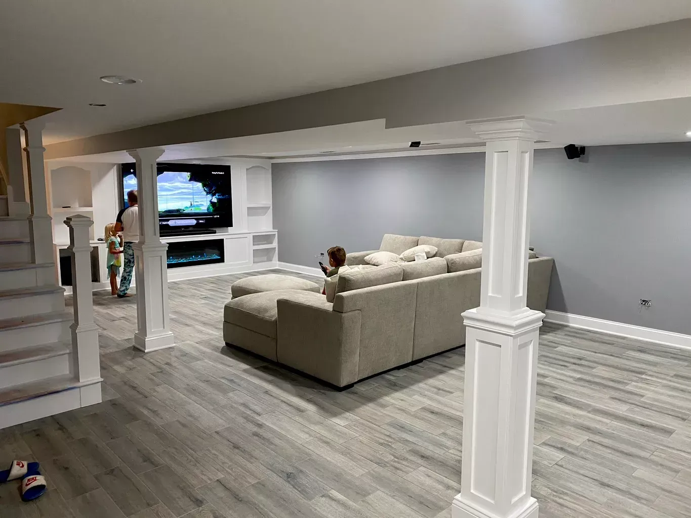 Modern living room with sectional sofa, TV, and gray wood-look floors