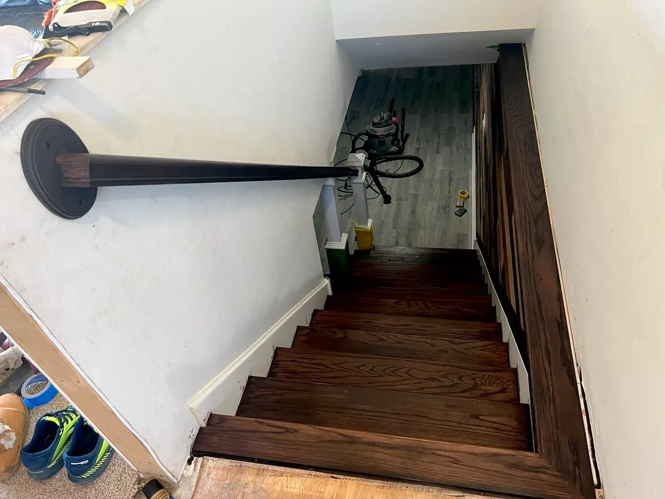 Steep stairwell with dark wooden steps, white walls, handrail, and a bicycle at the bottom.
