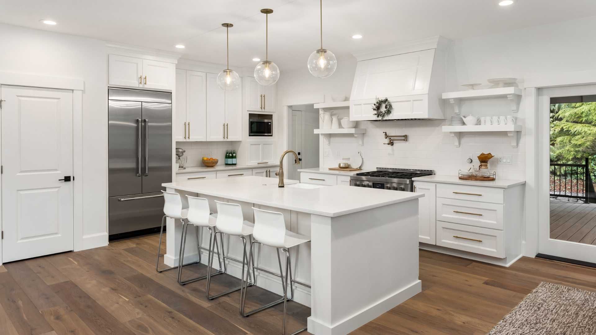 A kitchen with white cabinets , stainless steel appliances , a large island , and hardwood floors.