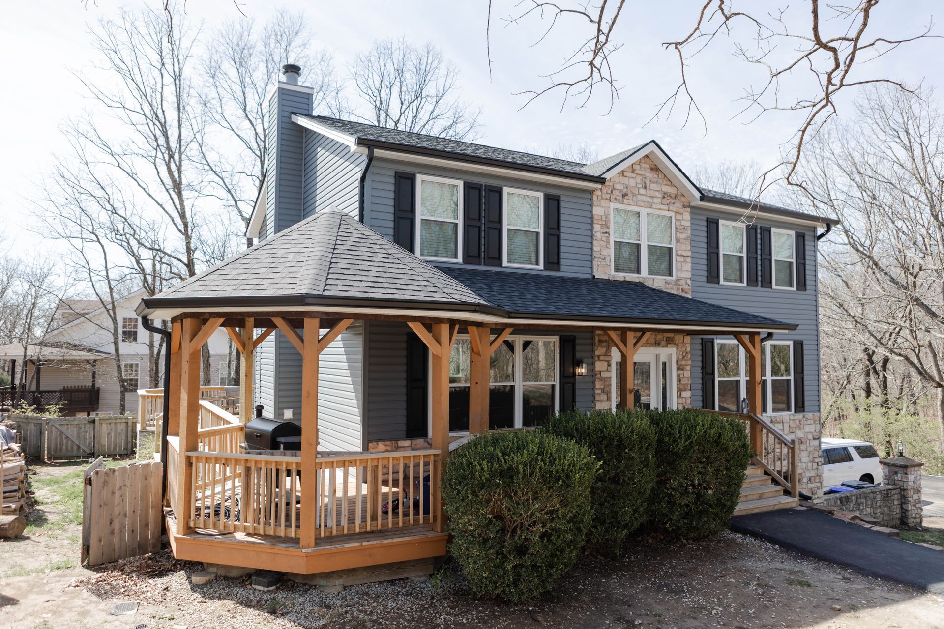 Two-story house with a gazebo-style porch, blue siding, and a brick facade section.