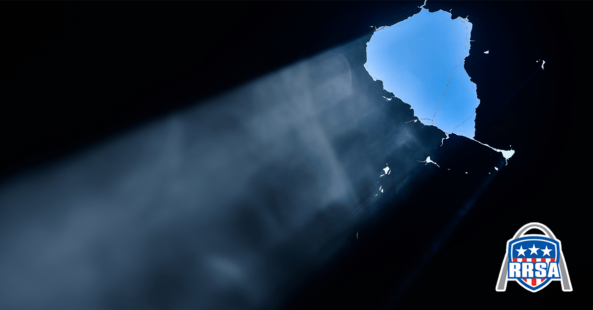 Bright light shines through a hole in a dark surface, revealing a map of Hawaii.