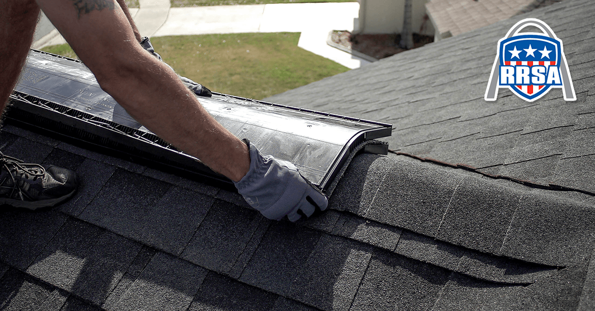 A roofer installing flashing on an asphalt shingle roof.