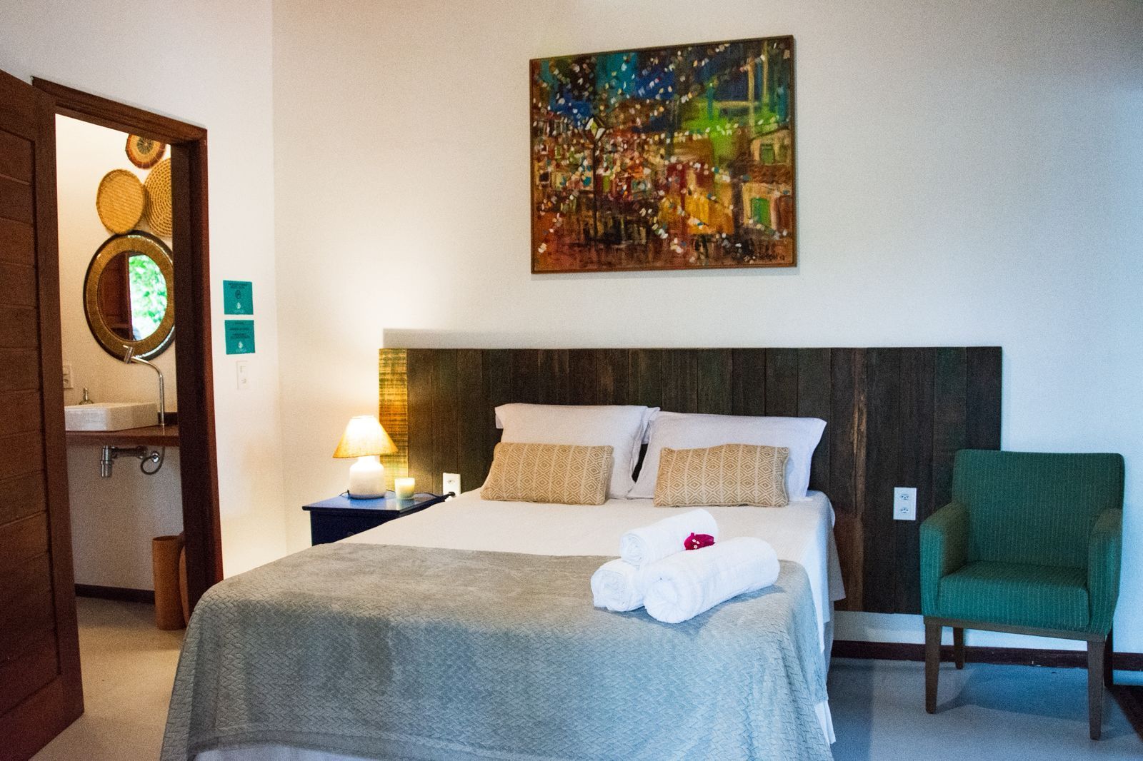 Quarto moderno com cama, luminária, arte de parede colorida e cadeira azul-petróleo.