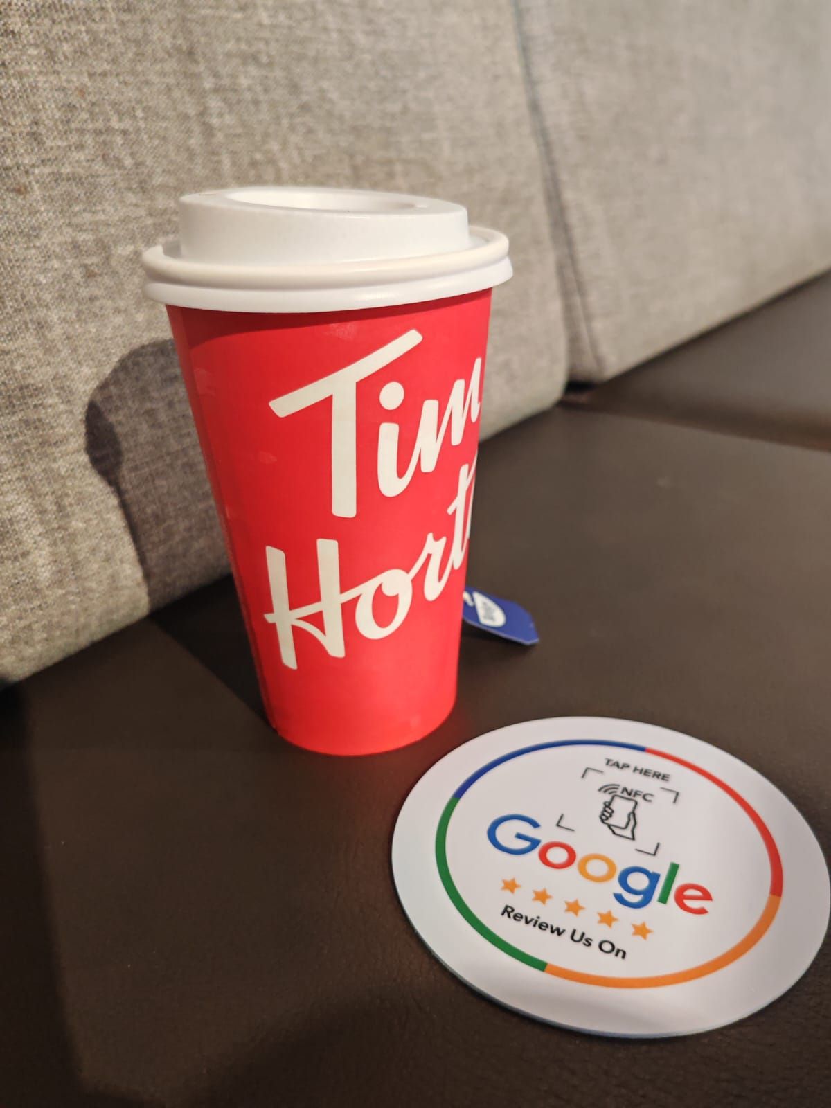 Red Tim Hortons coffee cup with white lid, next to Google 