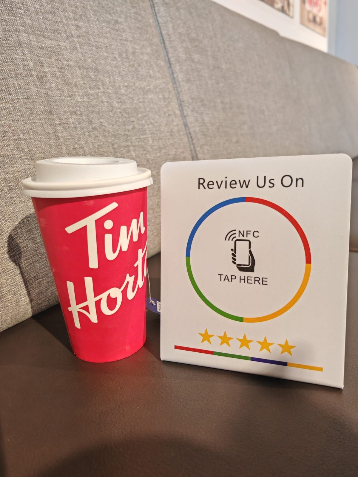 Tim Hortons coffee cup next to a sign encouraging customers to leave a review via NFC tap.