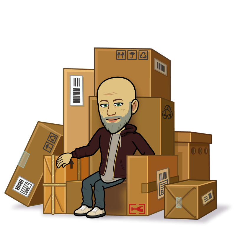 A man with a beard is sitting on a pile of cardboard boxes
