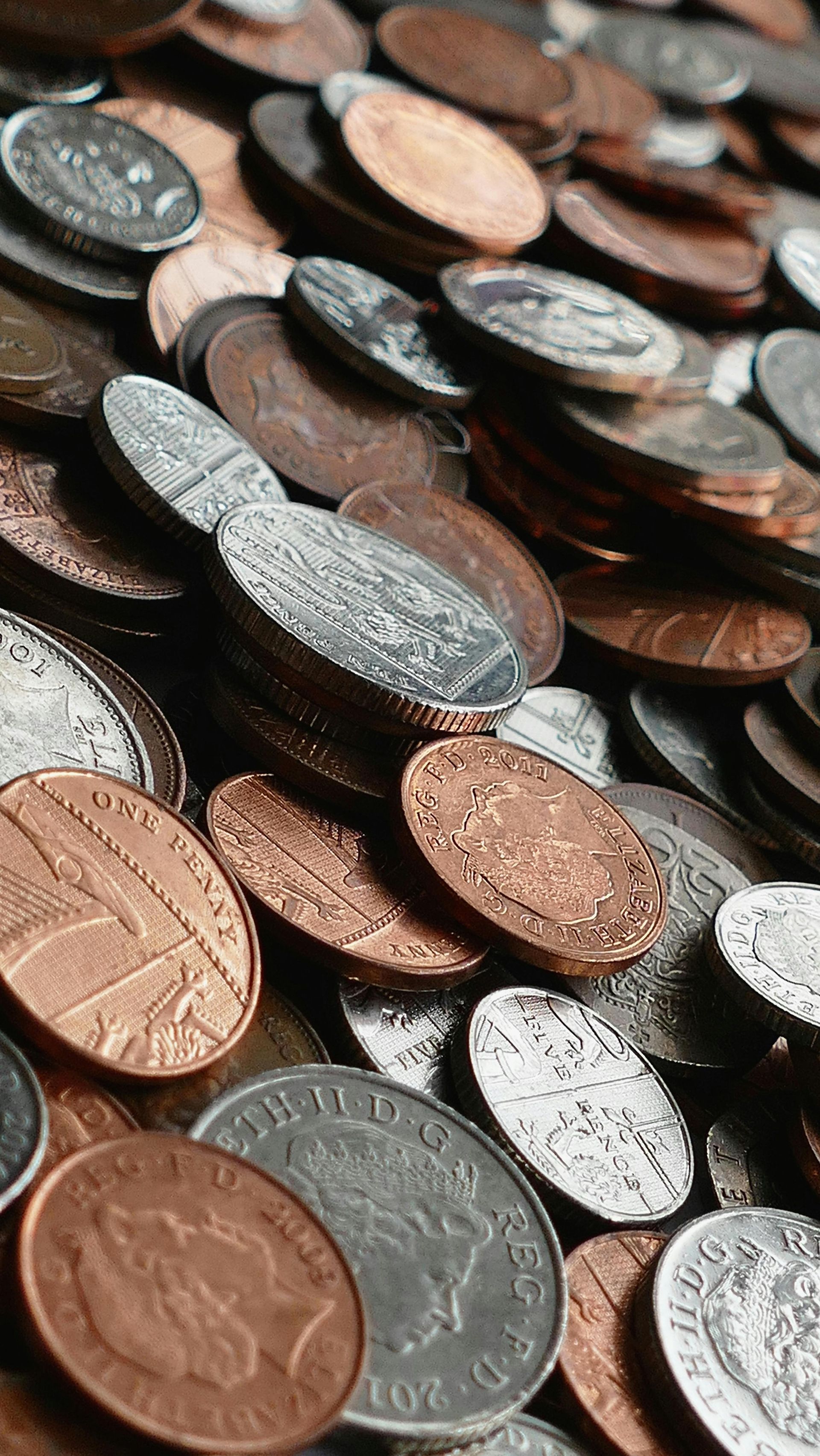Pile of mixed coins, including copper pennies and silver dimes, at close range.