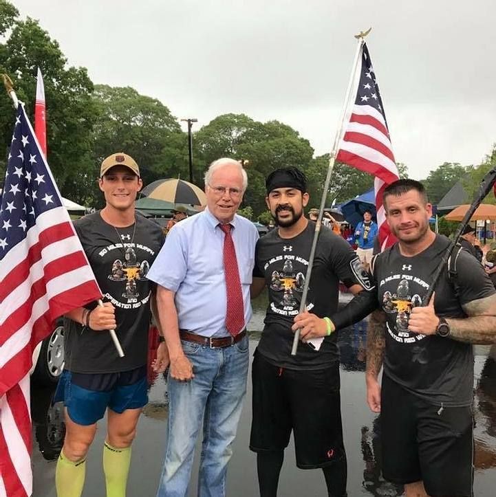 A group of men are posing for a picture while holding american flags
