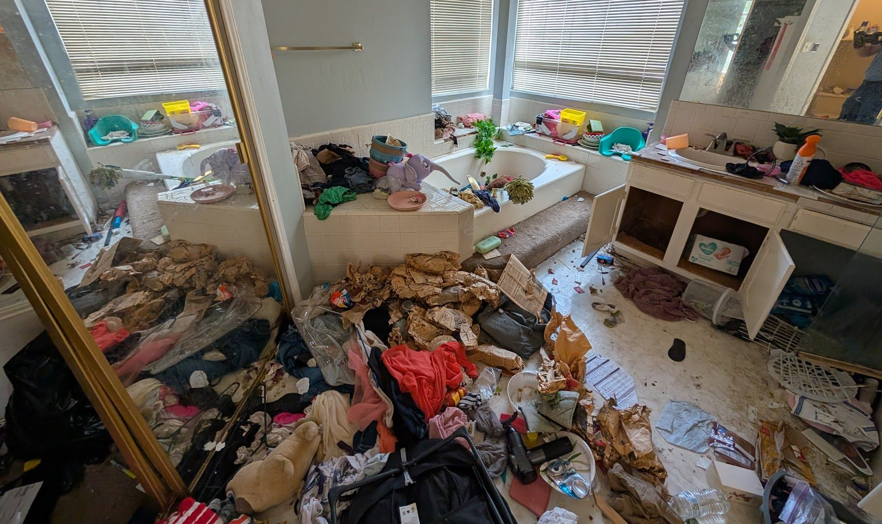The sun is shining through the window in a room filled with trash.