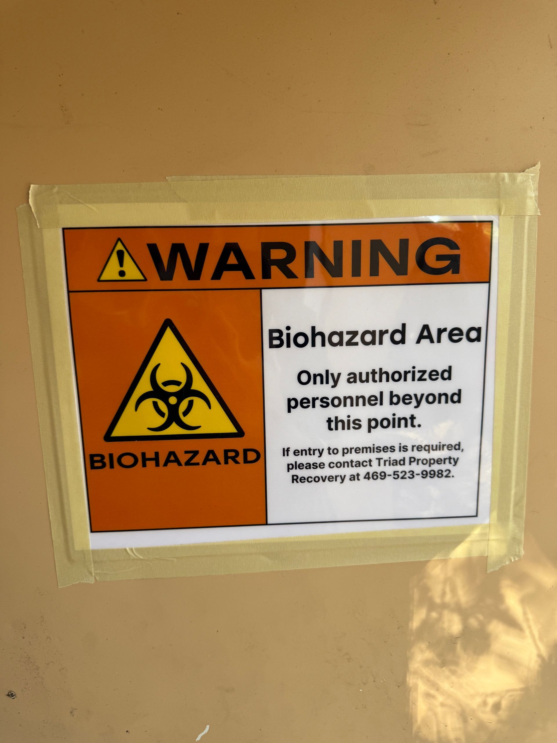 Warning biohazard area sign with yellow hazard symbol and restricted access notice on a wall.