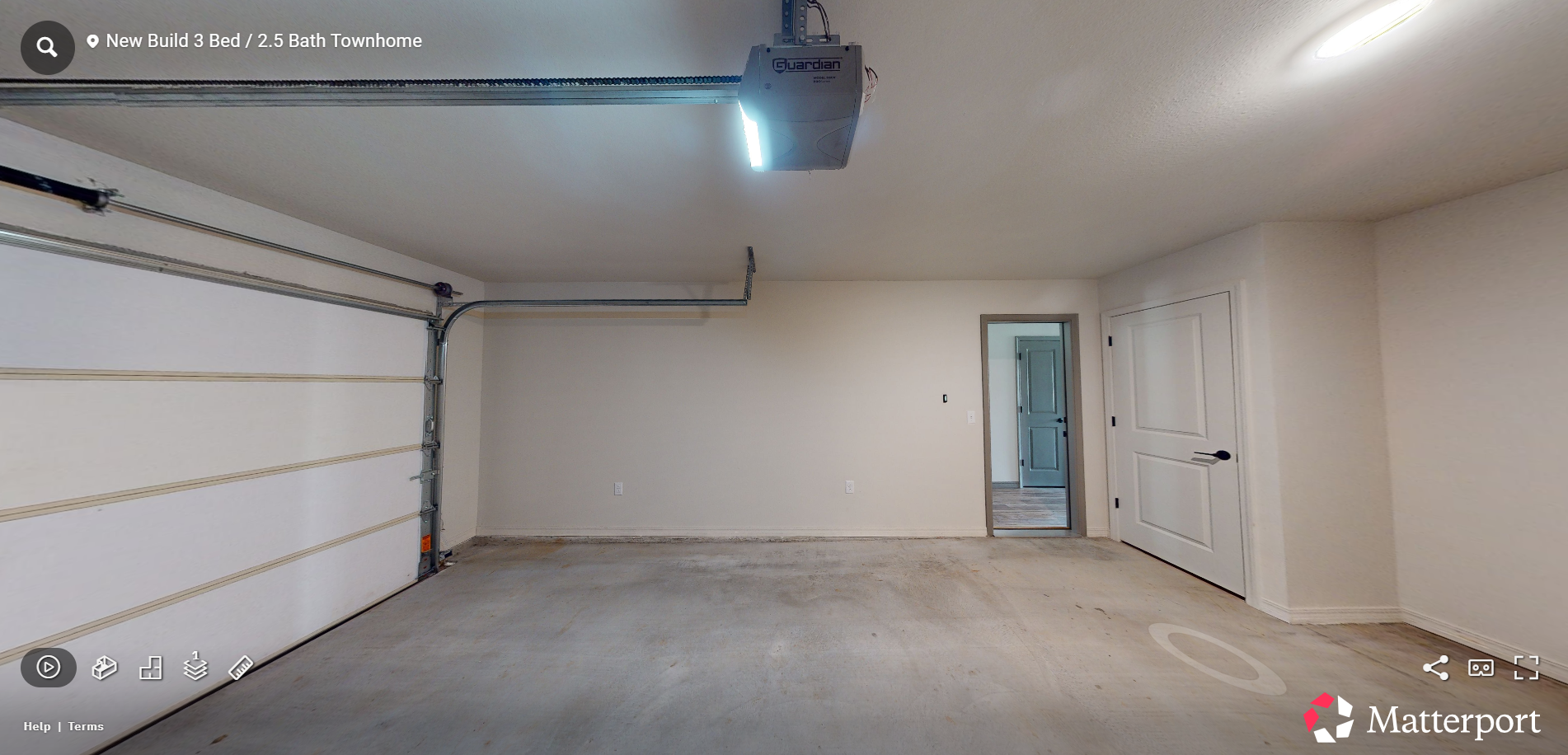 Empty two-car garage with white walls, concrete floor, and open door to a hallway.