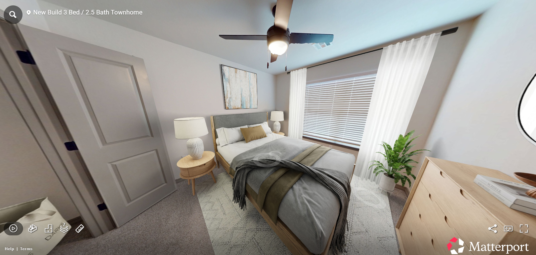 Bright bedroom with a bed, nightstand lamps, ceiling fan, window curtains, and a potted plant.