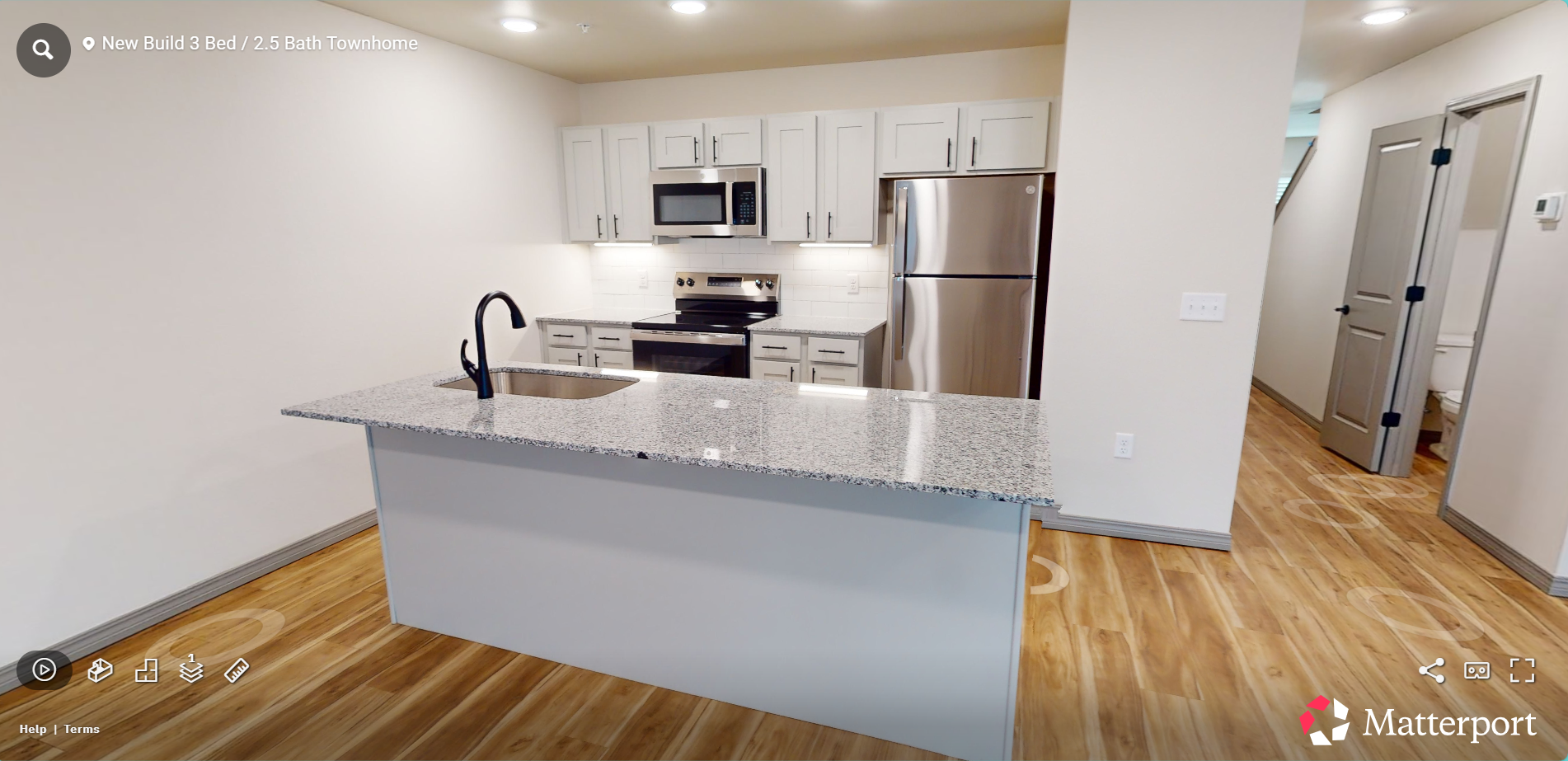 Modern kitchen with white cabinets, stainless steel appliances, granite island, and hardwood floors