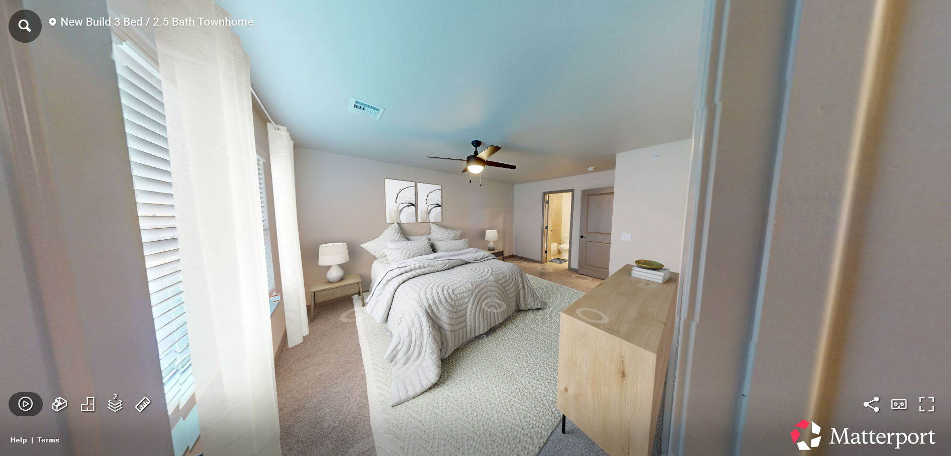 Bright bedroom with a bed, dresser, ceiling fan, and open doorway leading to a hallway
