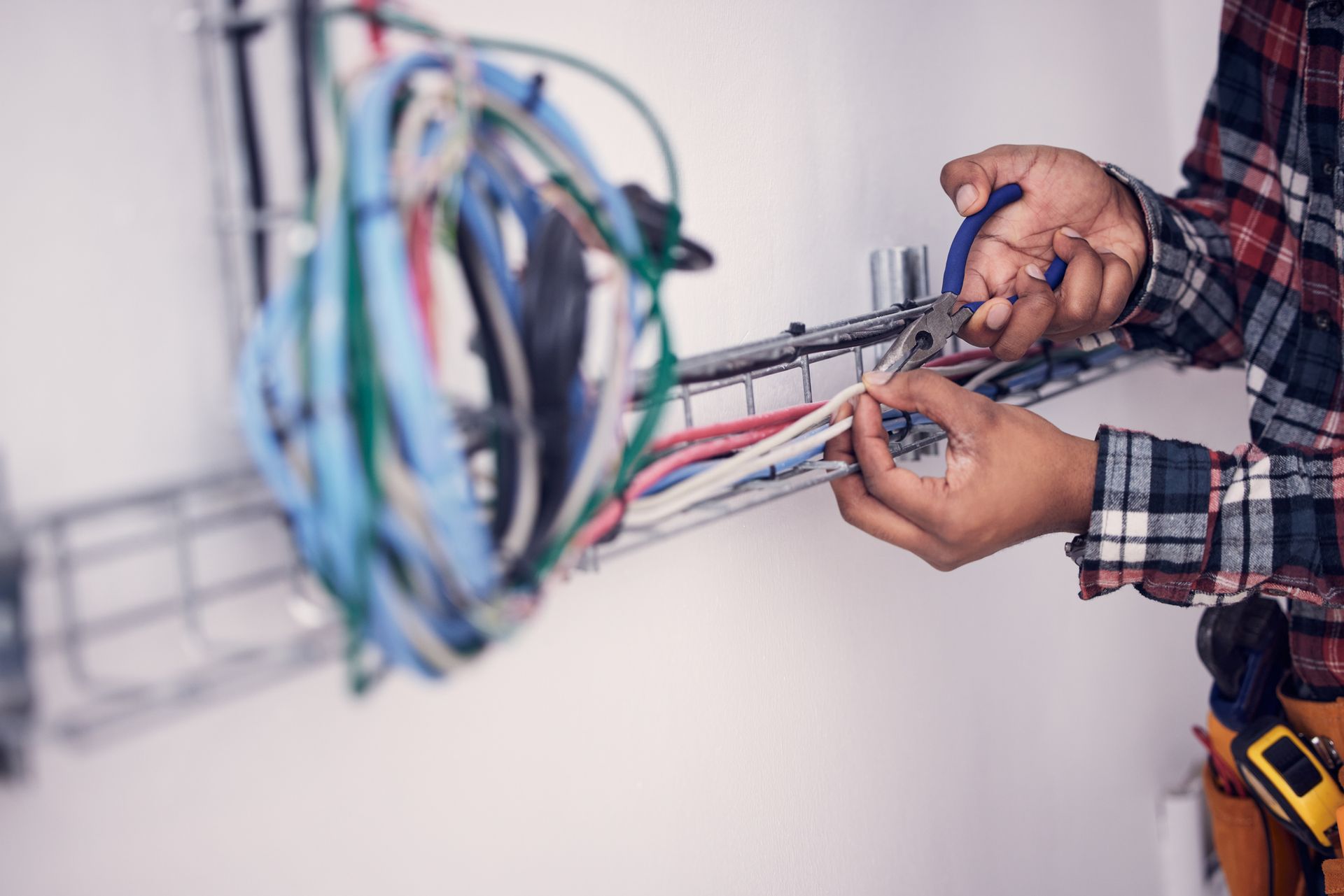 A man is cutting wires with a pair of pliers.