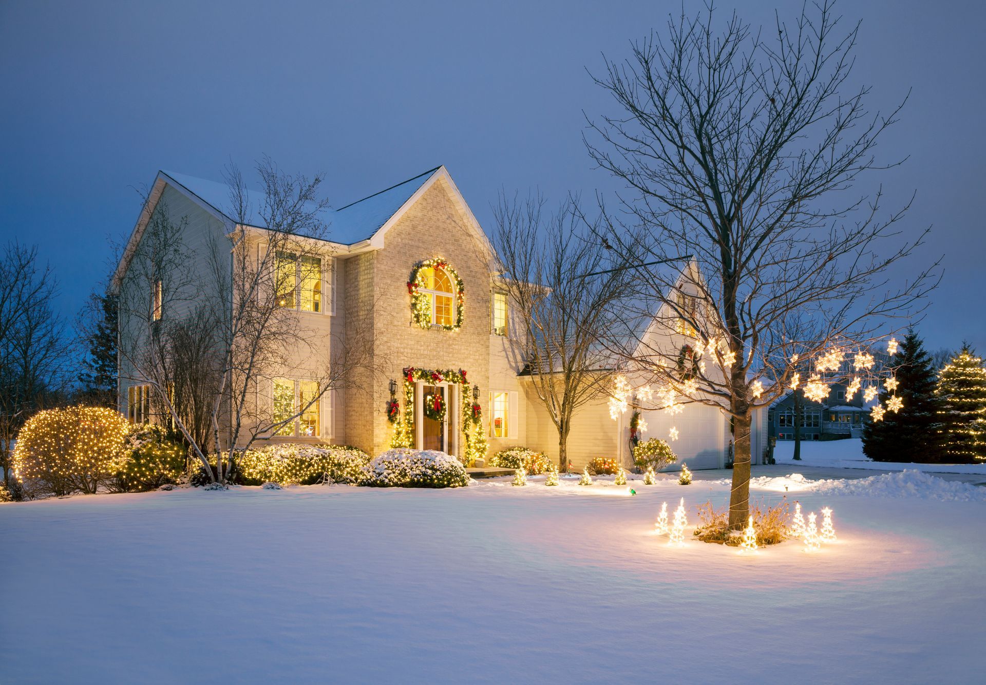 A large house is decorated with christmas lights in the snow.