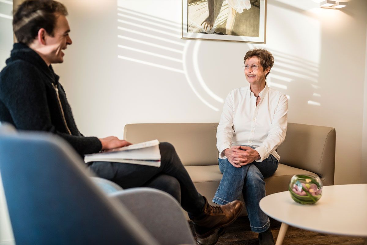 Ein Mann und eine Frau sitzen auf einem Sofa und unterhalten sich.