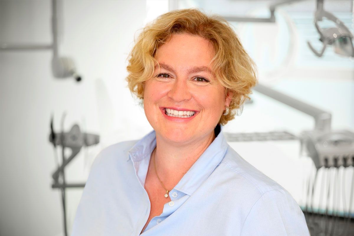 Zahnärztin Christina Krause lächelt in einer Zahnarztpraxis in die Kamera.