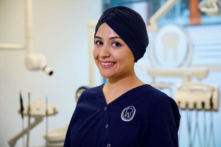 Eine Frau mit Turban lächelt in einer Zahnarztpraxis.