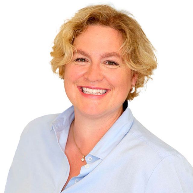 Zahnärztin Christina Krause in einem blauen Hemd lächelt in die Kamera.