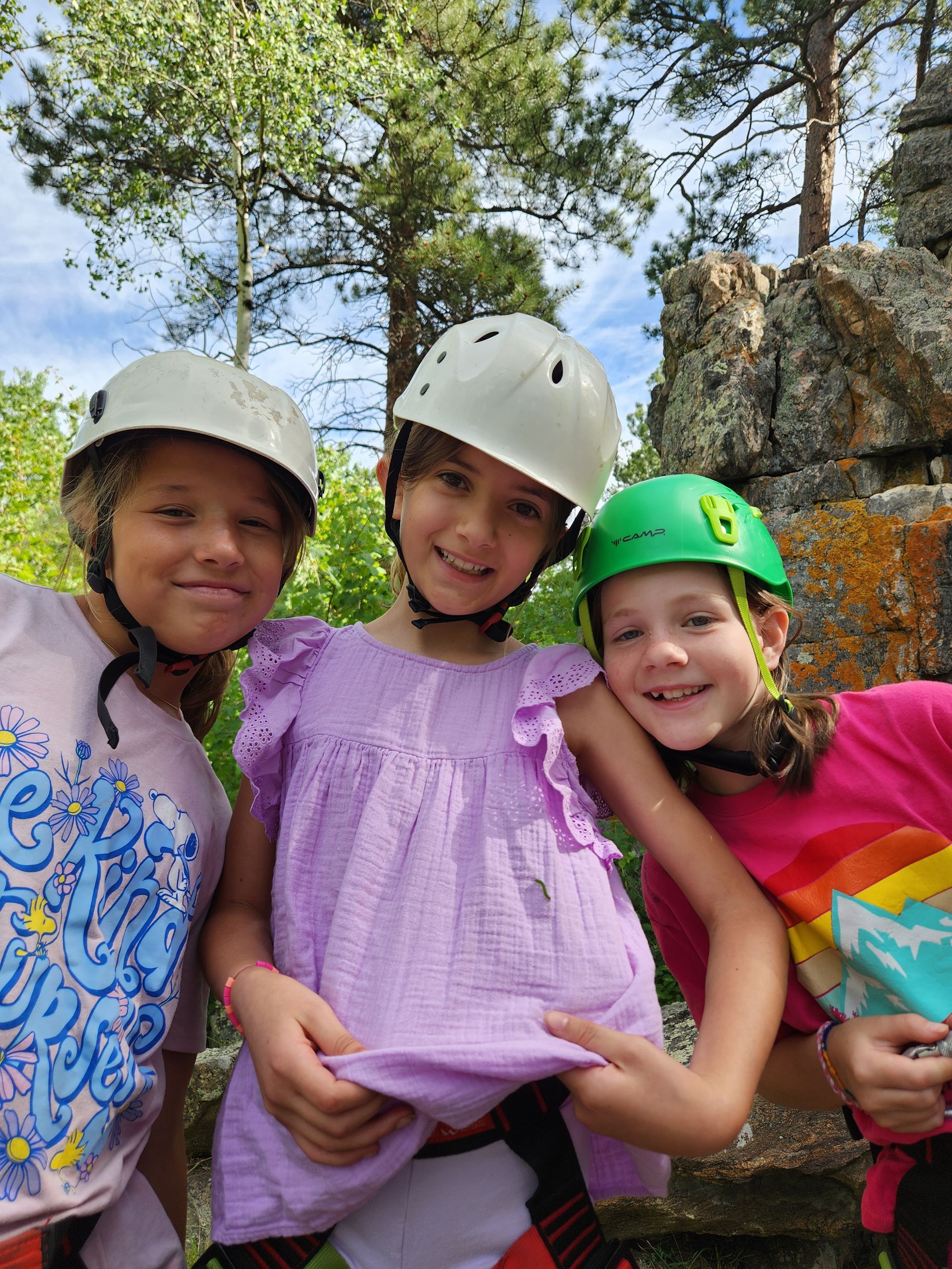 Campers smiling in rock climbing helmets.