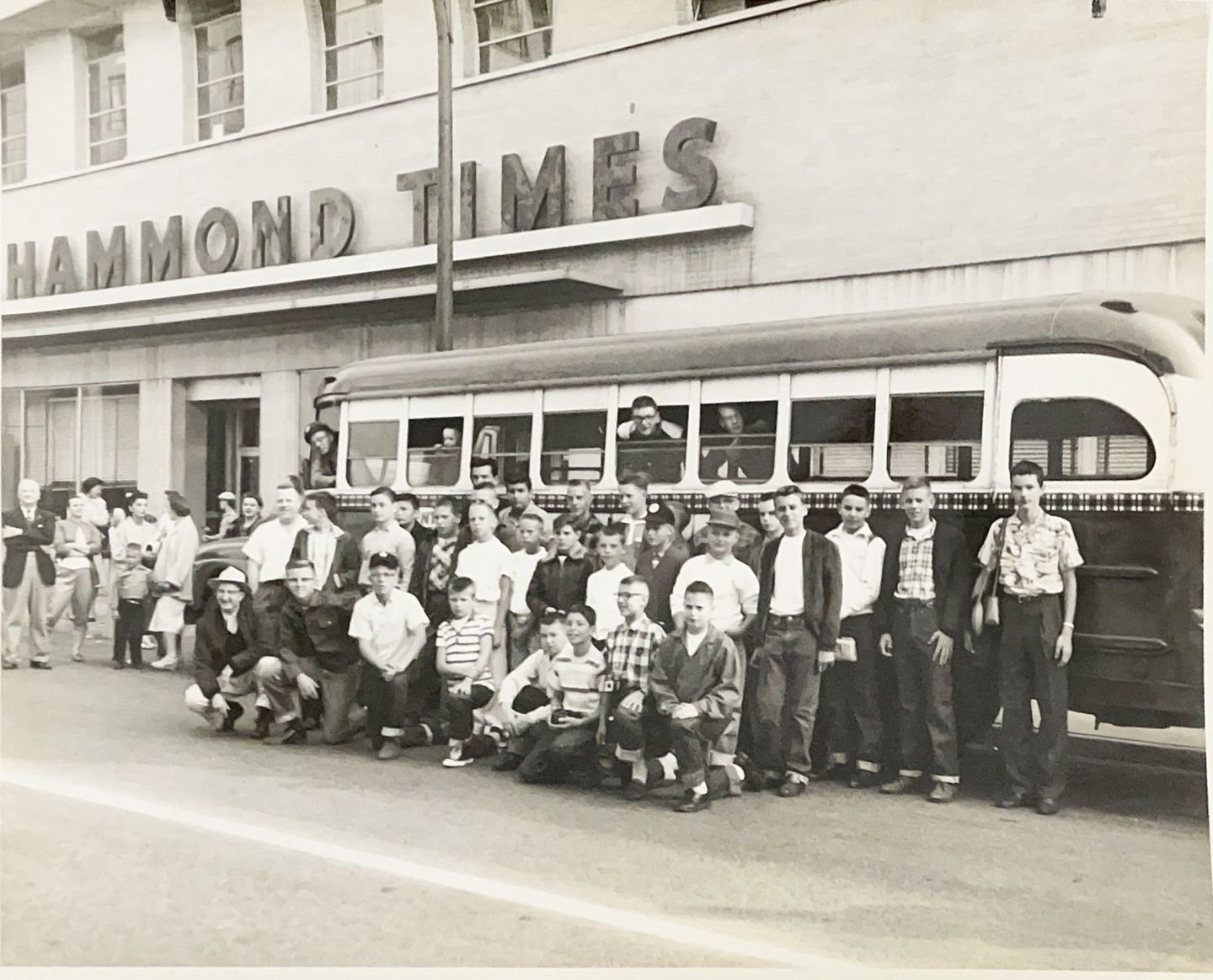 Black and white image of young boys standing by bus.