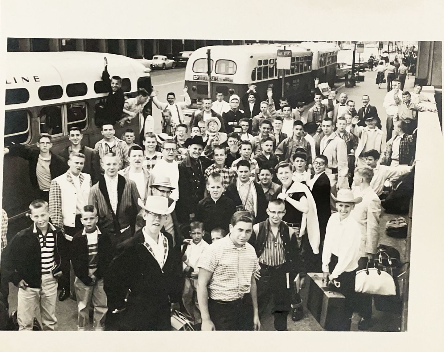 Black and white image of crowd at busy bus stop.