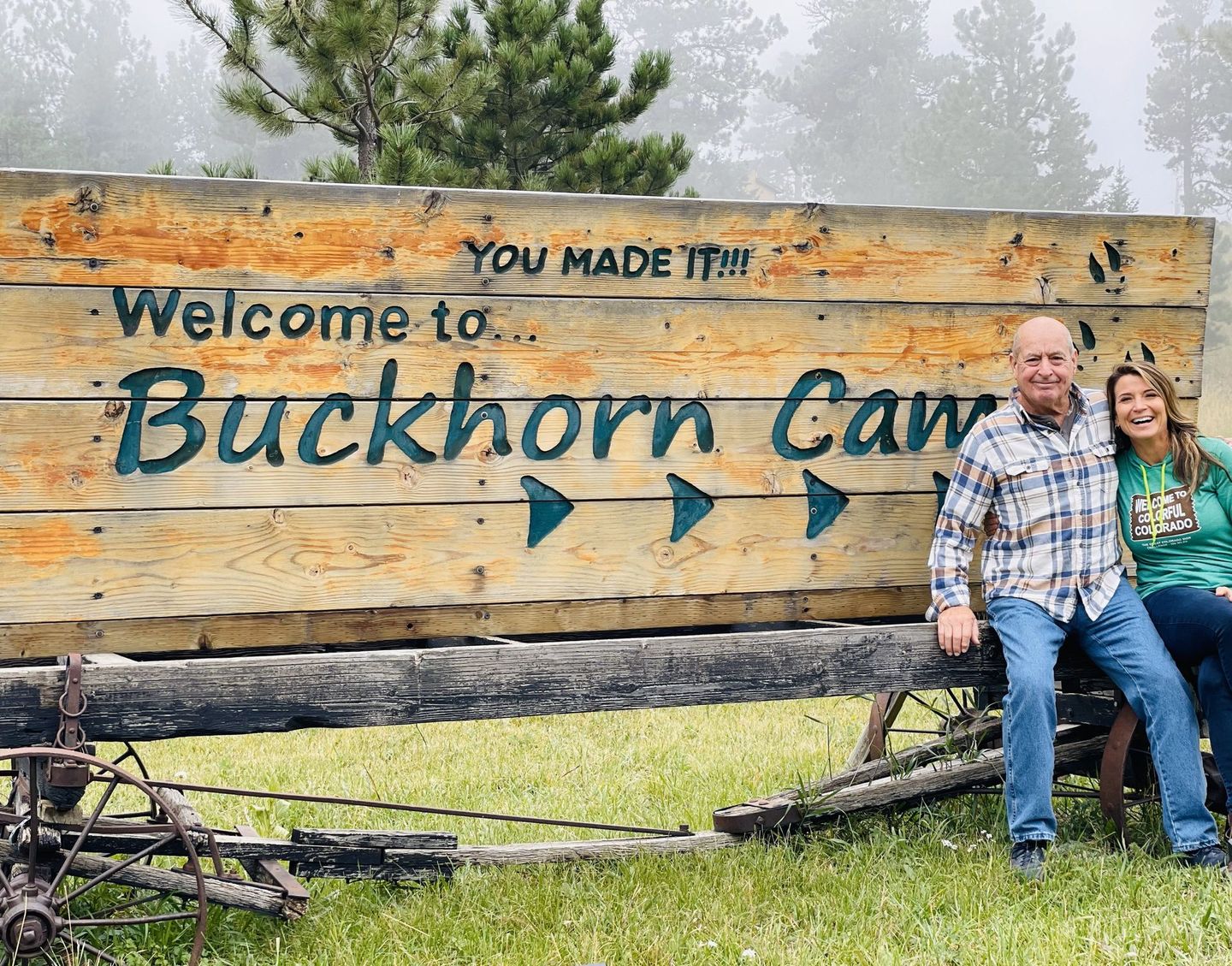 Man and women in front of wooden Buckhorn Camp sign.