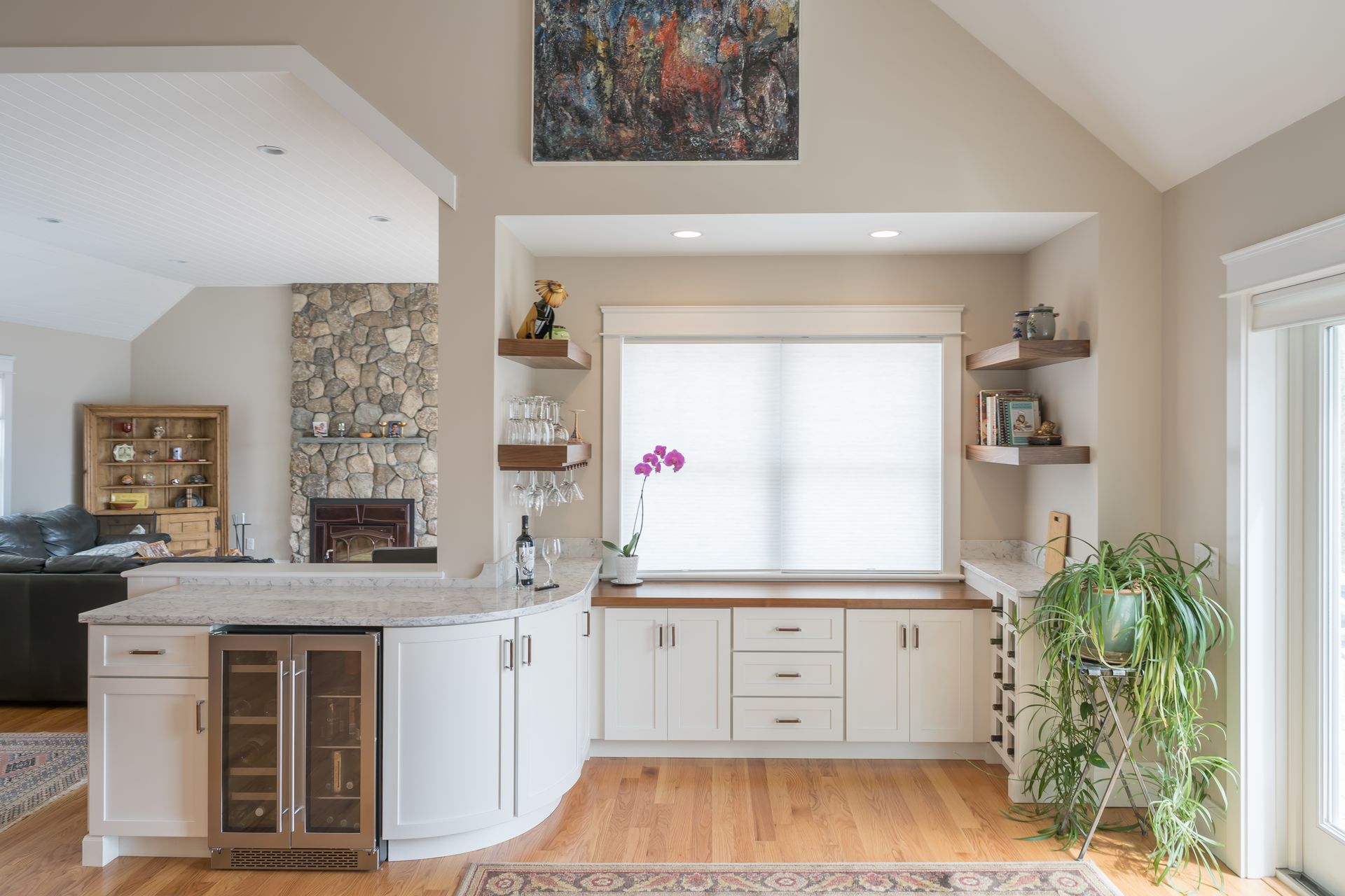 Bright modern kitchen with white cabinets, island, wine cooler, large window, and a potted plant