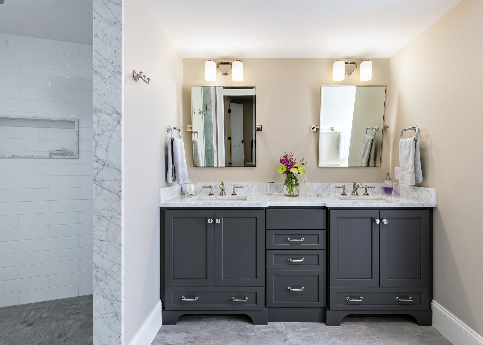 Bathroom vanity with dark cabinets, white countertop, and two mirrors under wall sconces