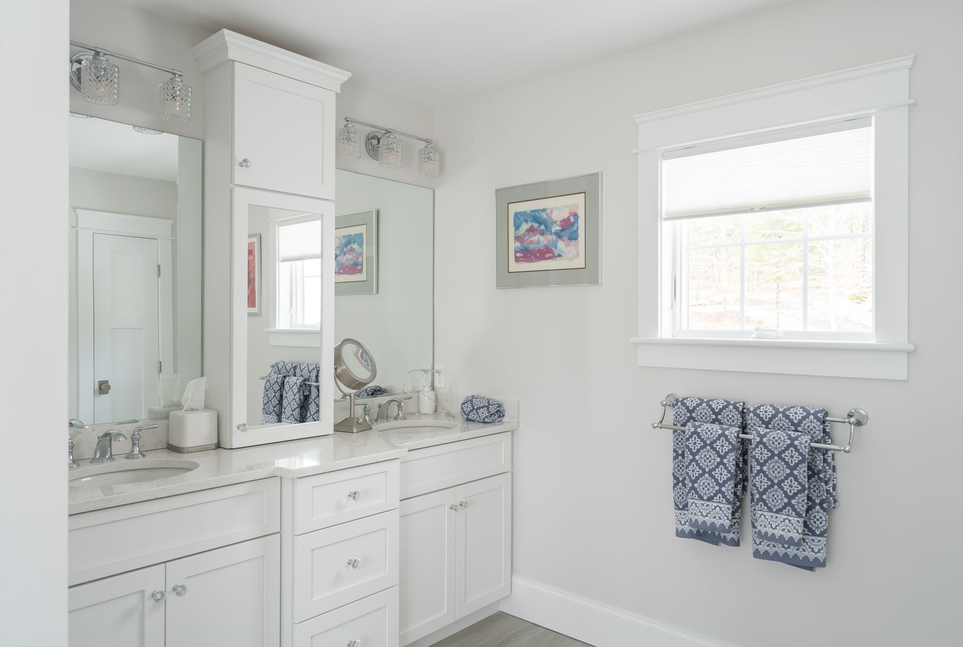Bright white bathroom vanity with mirror, blue accents, and a window with blinds