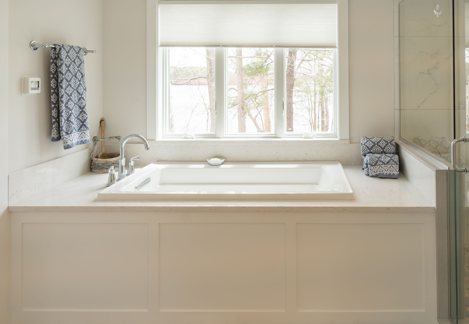 Bright bathroom with a freestanding tub under a window and white cabinetry.