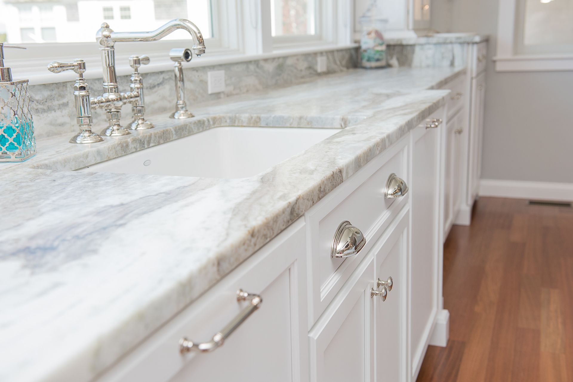 Bright white bathroom vanity with marble countertop, silver faucet, and hardwood floor